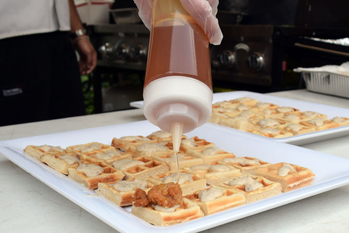 Spreading honey on southern chicken and waffler appetizers
